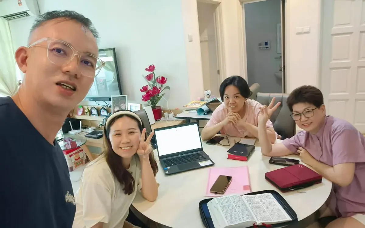 Pastor Jony with three believers around a table with Bibles and a laptop